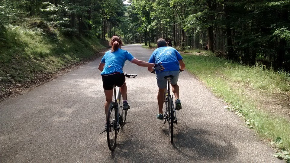 One cyclist pushing another whilst pedalling along a road in France